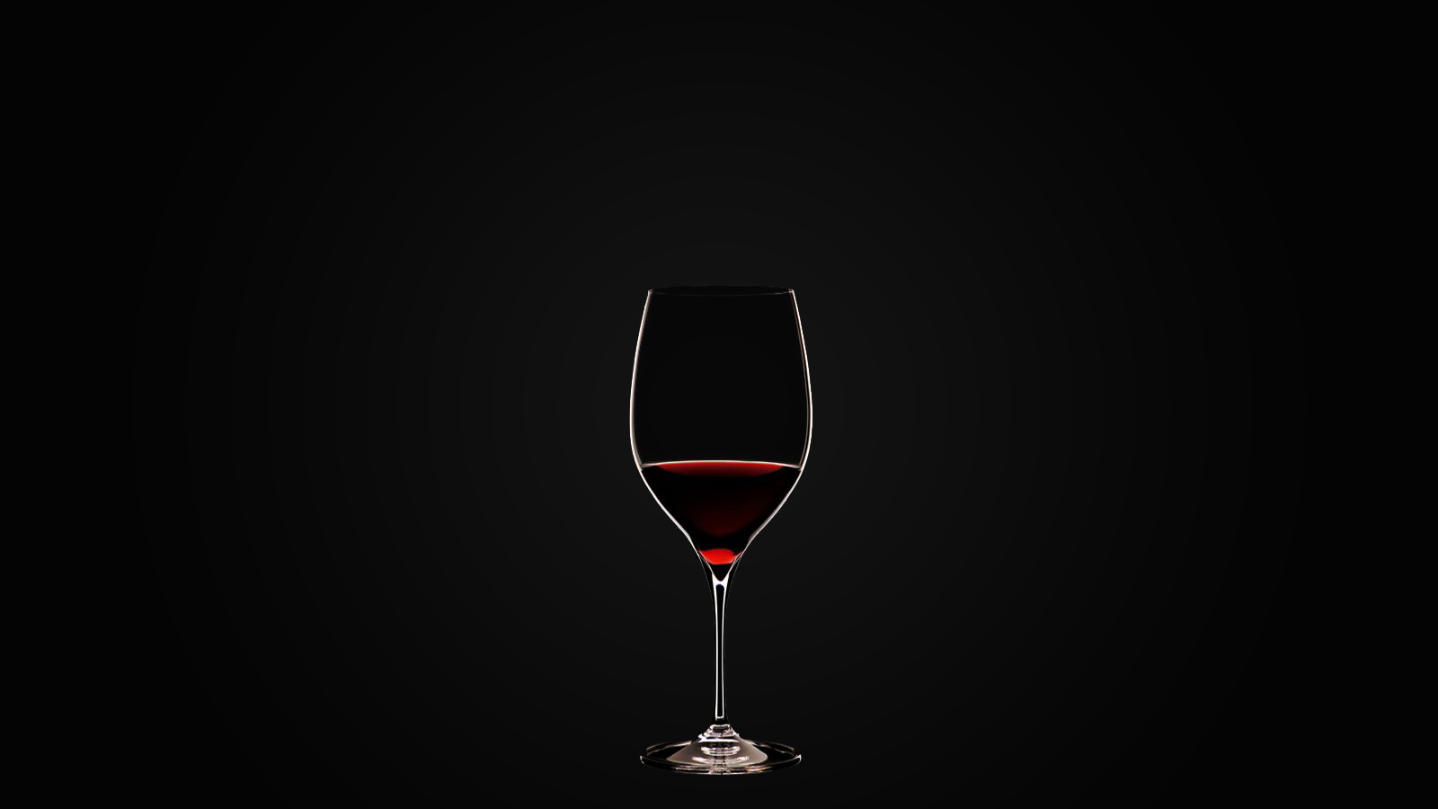 A glass of red wine against a black background